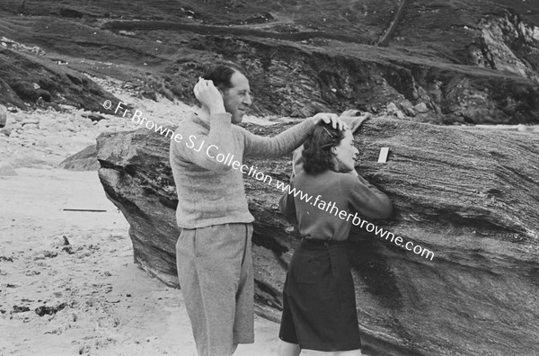 AT THE BEACH GIRL AND MAN COMBING THEIR HAIR